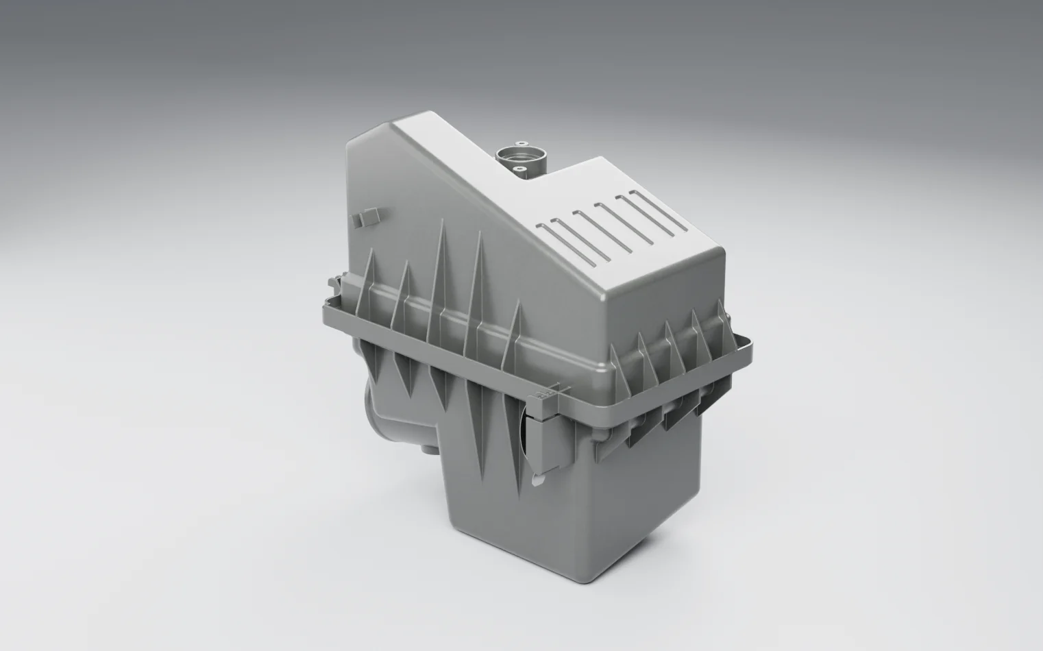 A black plastic engine air filter housing on a grey studio floor: a ribbed lower box and a cover with its outlet, held together by metal latch clips